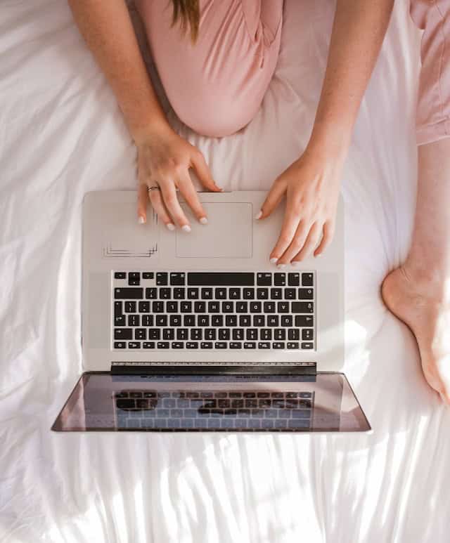 person sat on a bed looking at a laptop